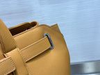 Tan leather tote bag detail with blue D-ring clasp and edge stitching