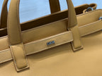 Close-up of tan leather tote front with Dior logo plaque