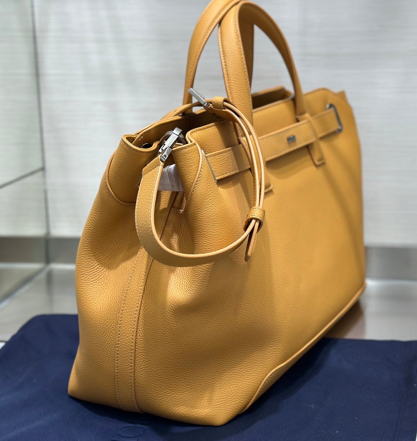 Tan leather tote bag with short handles and adjustable shoulder strap