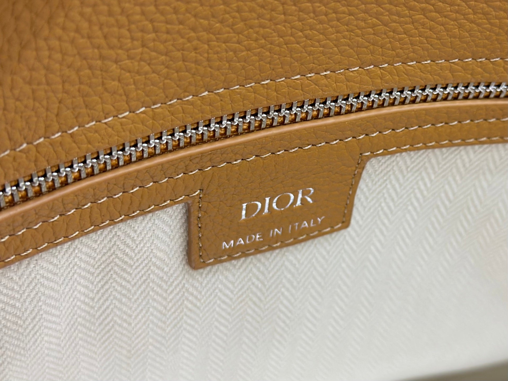 Dior Made in Italy label on tan leather with zipper trim close-up