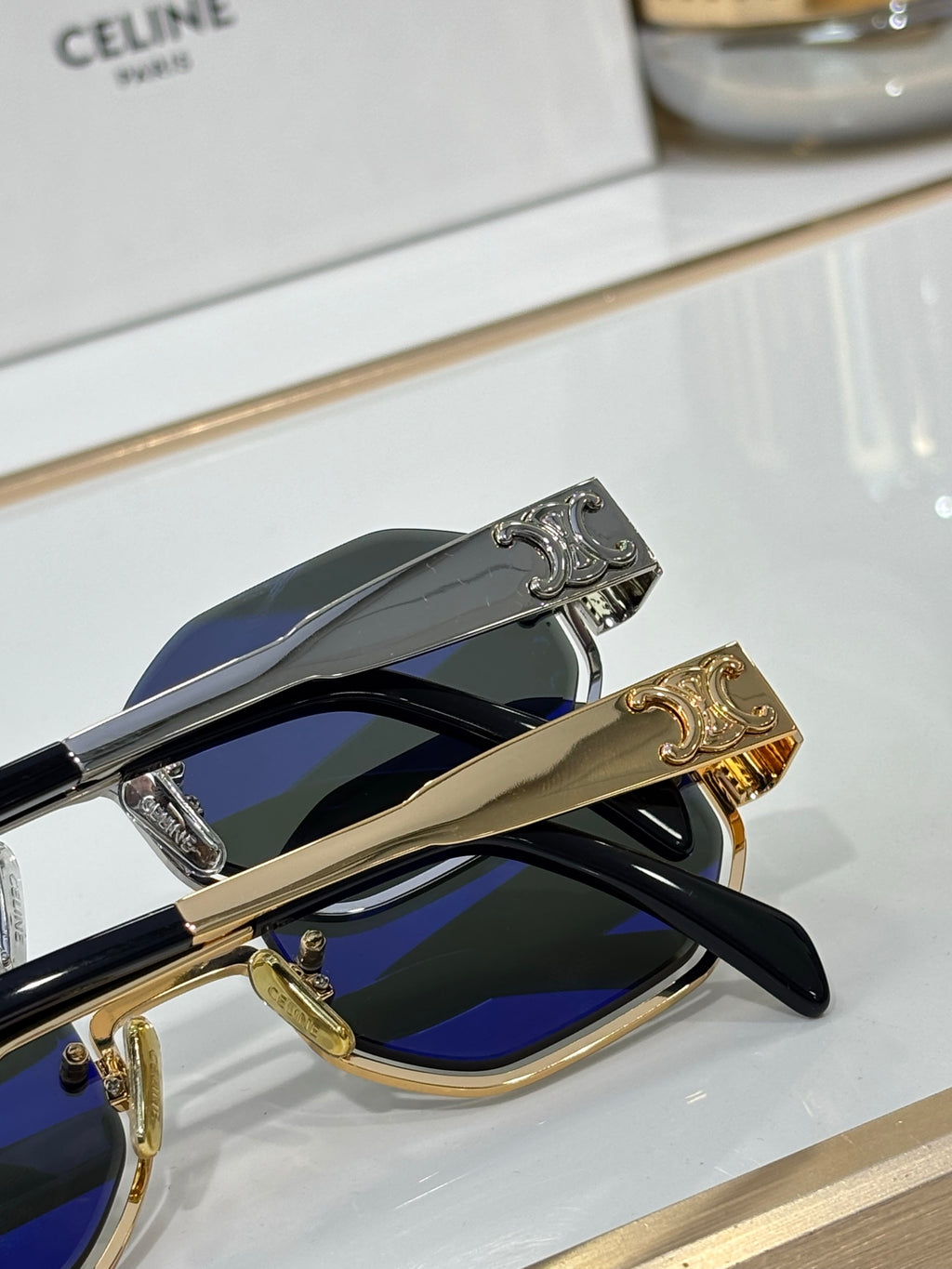 Celine sunglasses detail view: gold and silver temples with logo, blue-tinted lenses