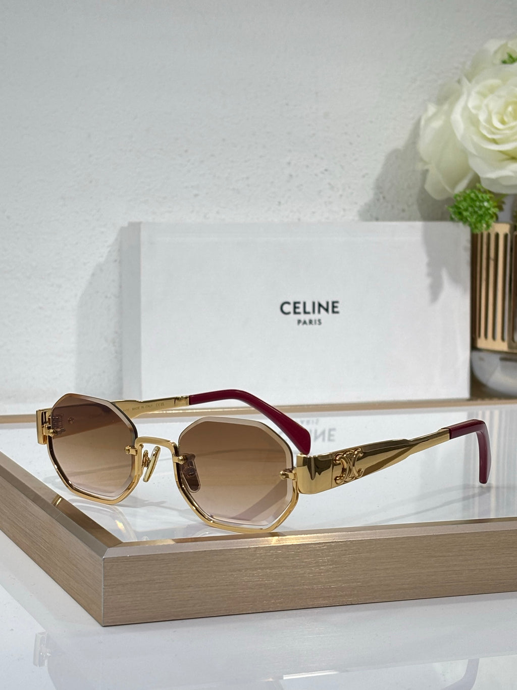 Celine sunglasses with gold-tone frames, red temples, and brown-tinted lenses