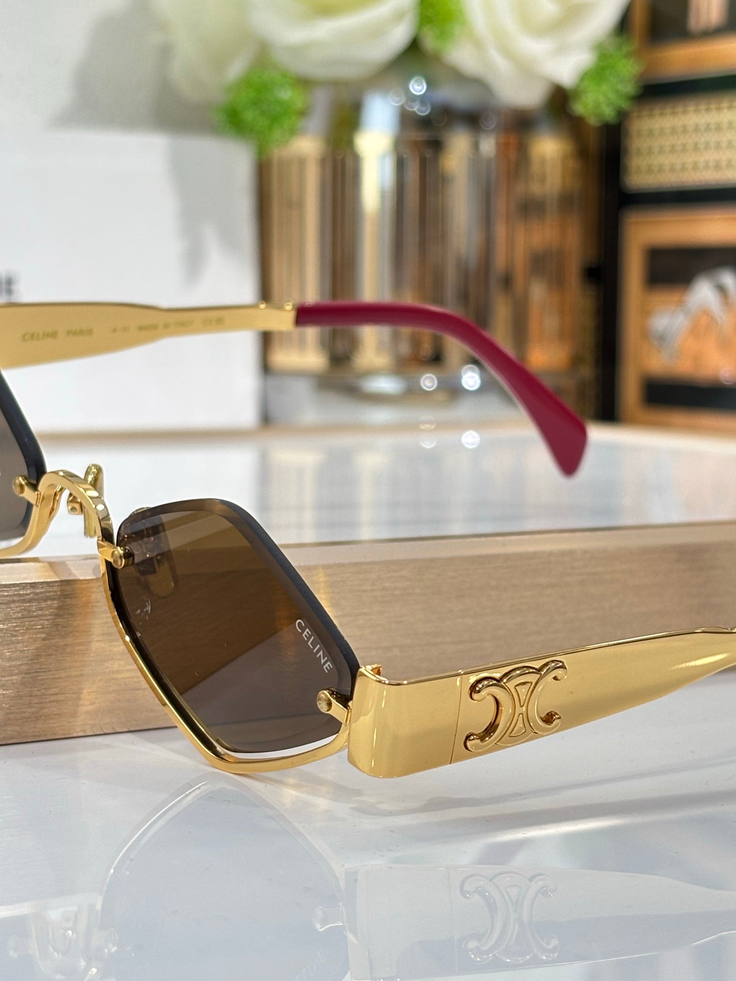 Celine eyeglasses close-up with gold frame, dark lenses and burgundy side temple.