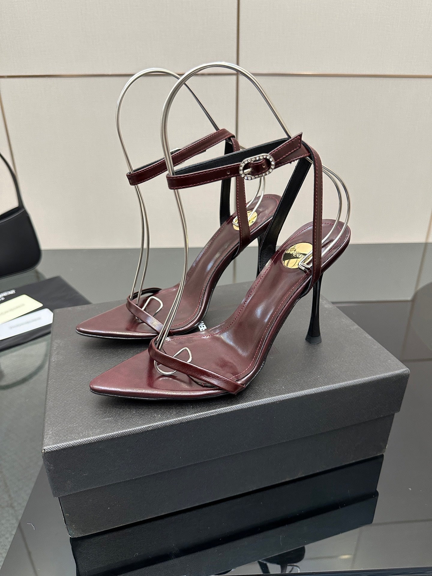 Burgundy strappy high-heel sandals with thin stiletto heels and circular heel loops