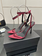 Pink stiletto heeled sandals with black straps and silver wire frame at back
