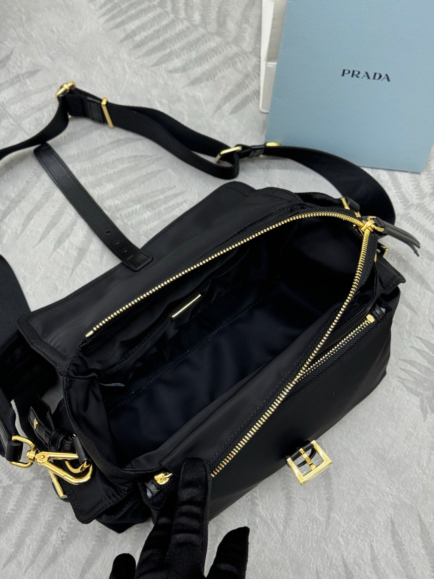 Prada black nylon crossbody bag with long strap, gold zippers, and front buckle