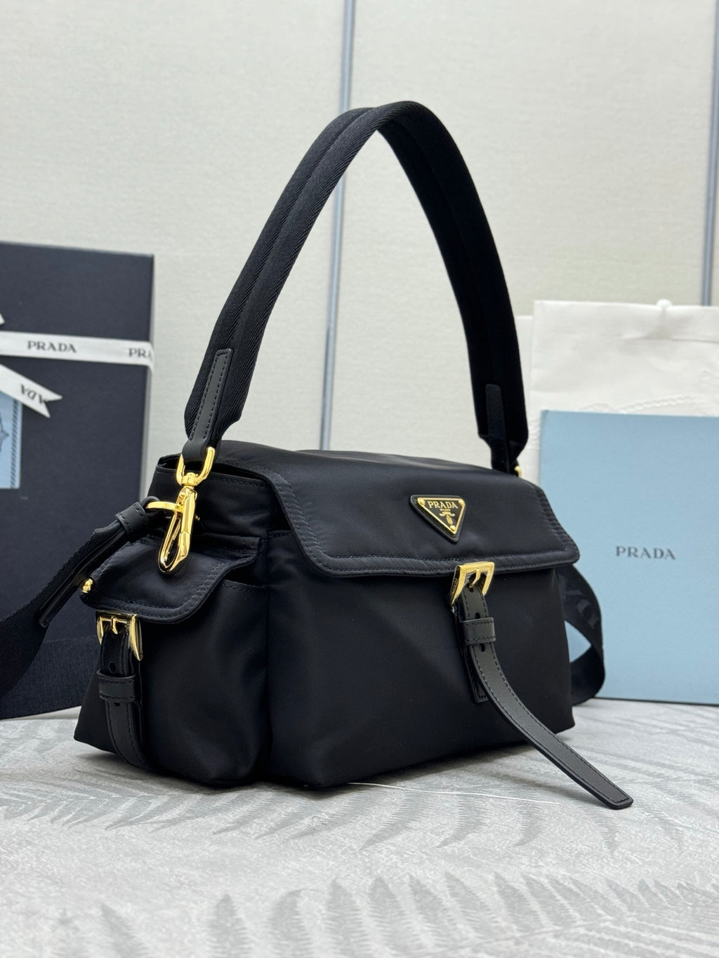 Prada black nylon bag with flap pocket, gold logo plaque, and adjustable crossbody strap