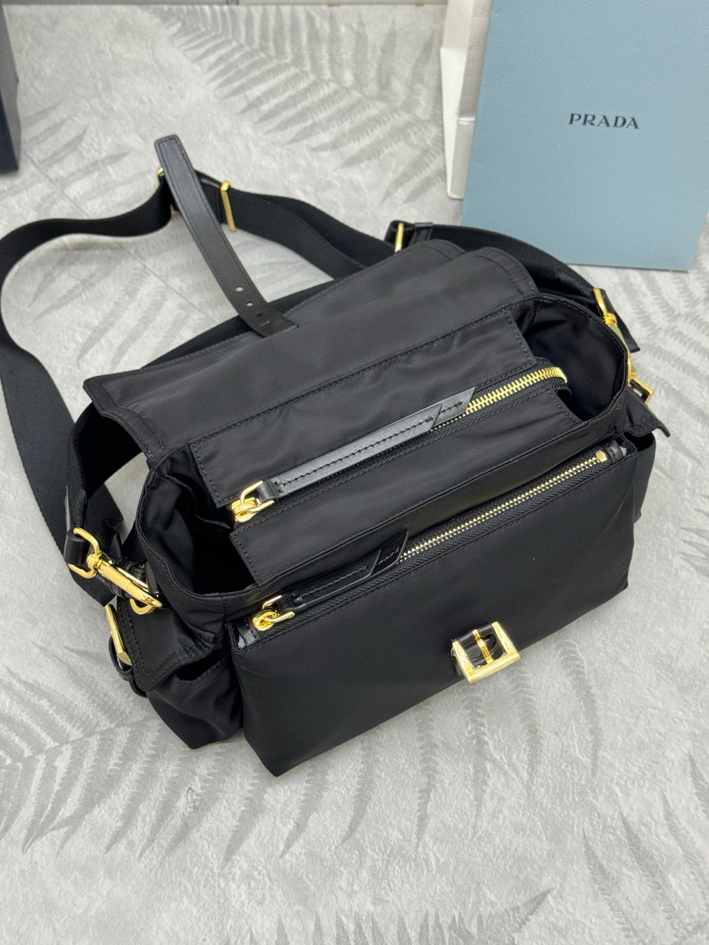 Prada black nylon shoulder bag with front zip pocket, gold zipper pulls, and strap