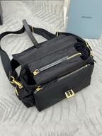 Prada black nylon shoulder bag with front zip pocket, gold zipper pulls, and strap