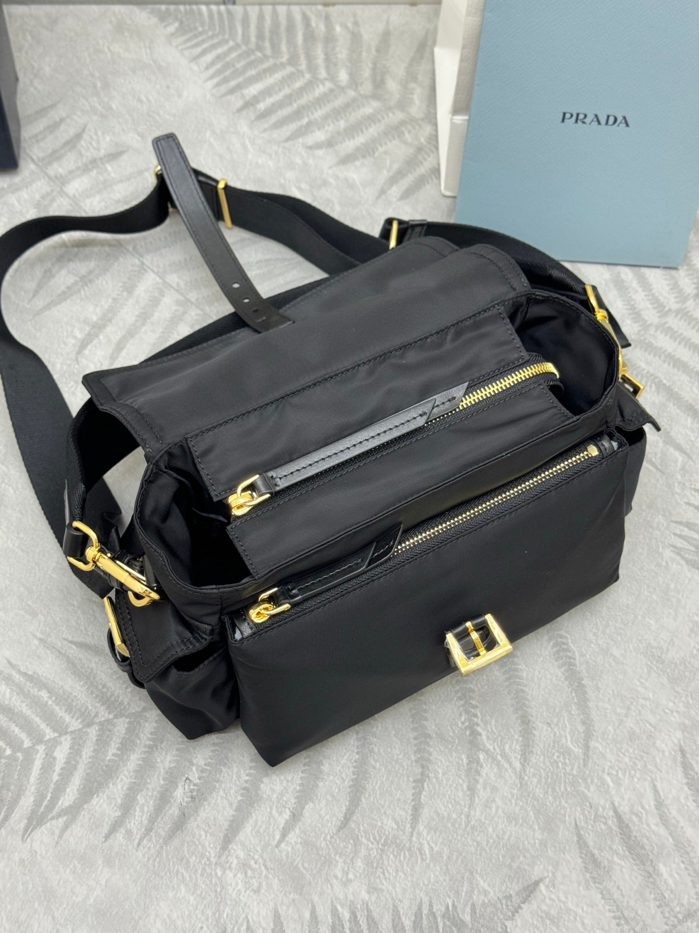 Prada black nylon shoulder bag with front zip pocket, gold zipper pulls, and strap