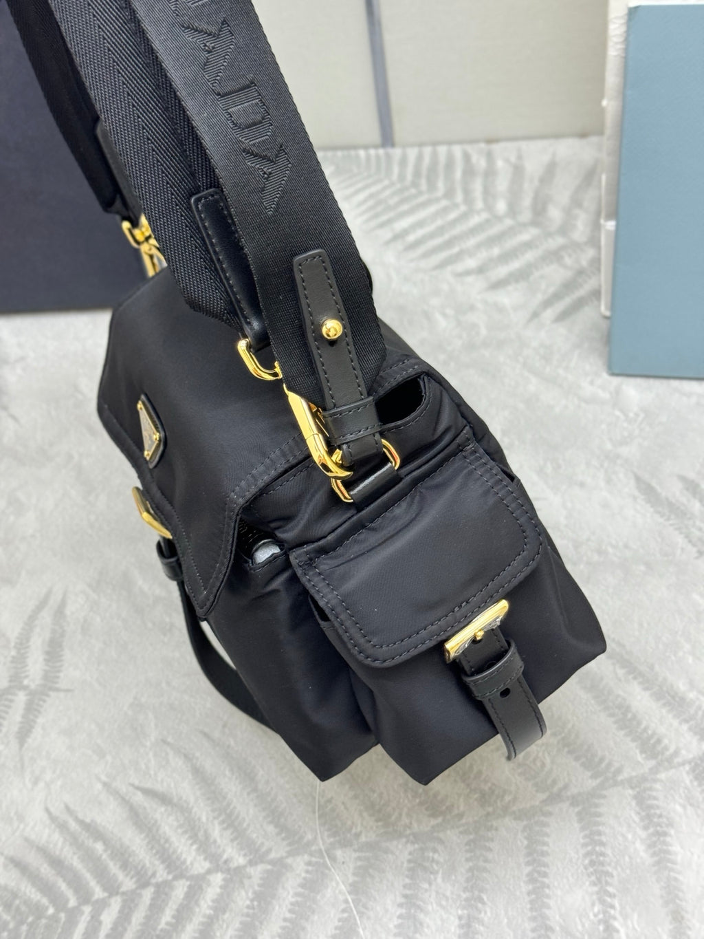 Prada black nylon shoulder bag with chain strap, side handle, and buckle charm