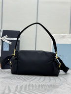 Prada black nylon shoulder bag with curved top handle, crossbody strap, and gold accents