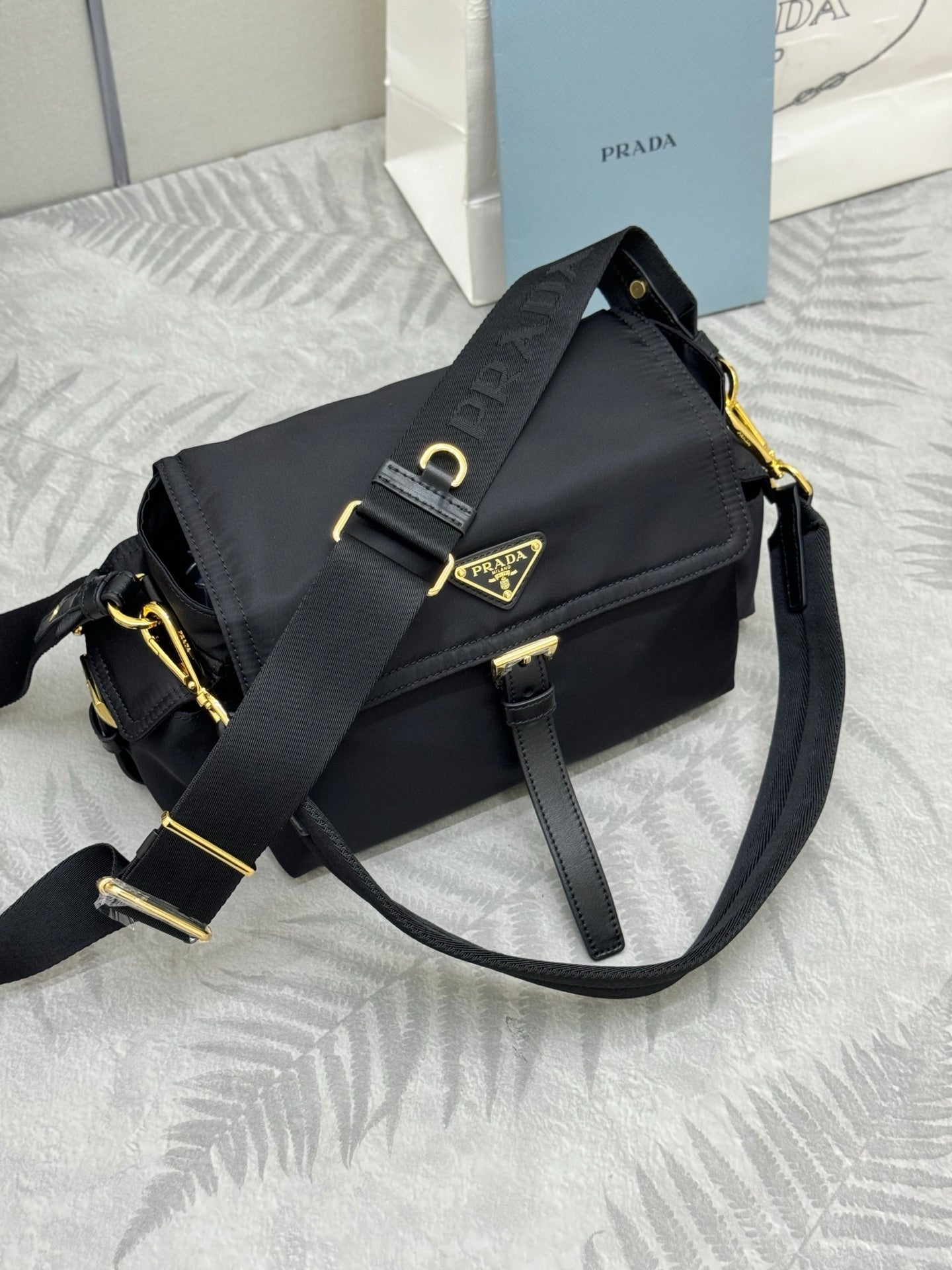 Prada black nylon bag with foldover flap, two straps, and gold buckle detail
