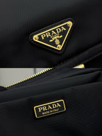 Prada black nylon bag close-up of gold logo plaques and zipper pull