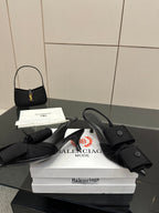 Black mules with wrap straps and low block heel, resting on white boxes