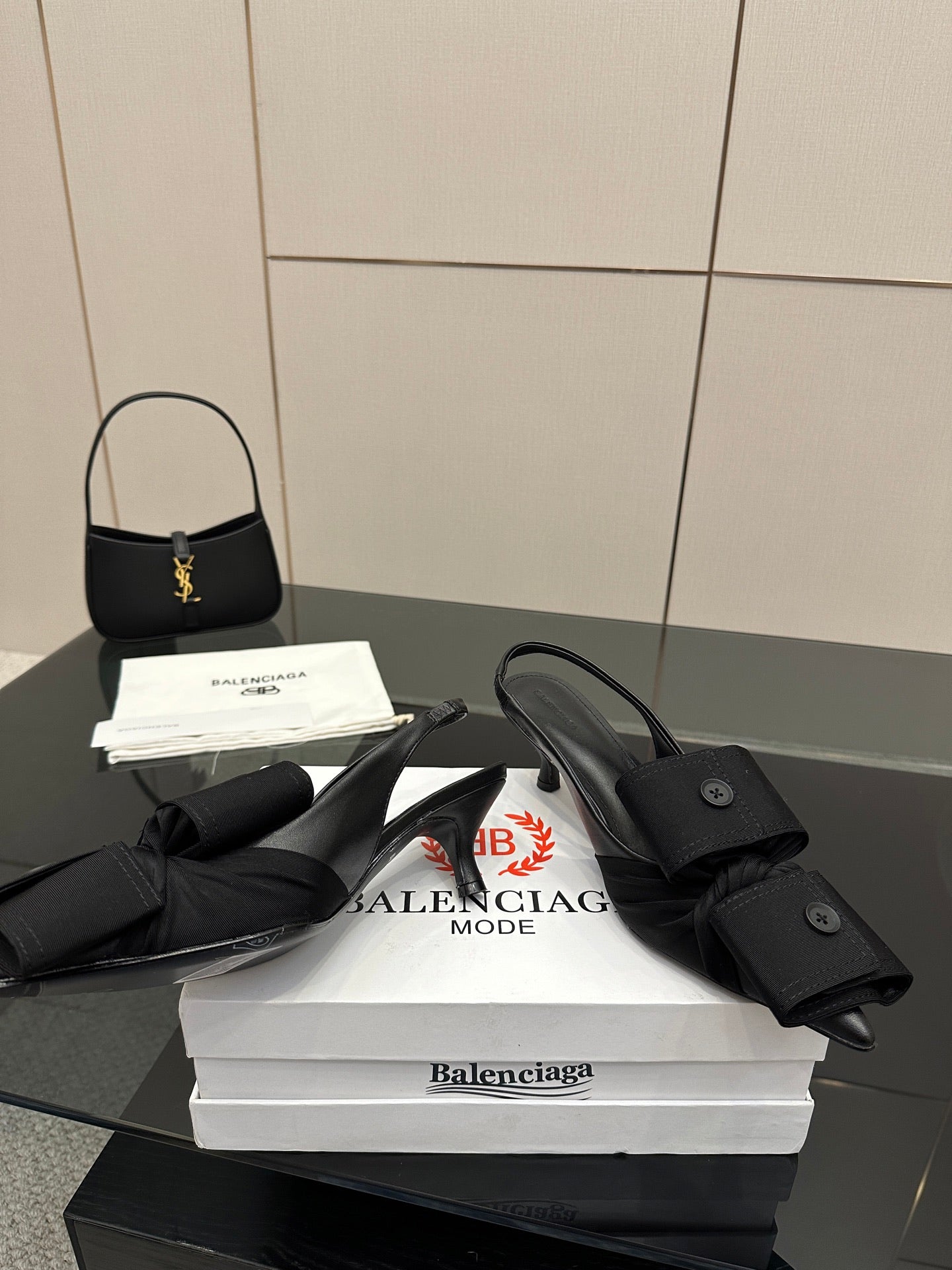 Black mules with wrap straps and low block heel, resting on white boxes