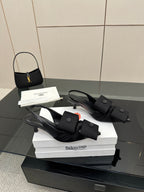 Pair of black mules with adjustable ankle strap and low block heel, on box