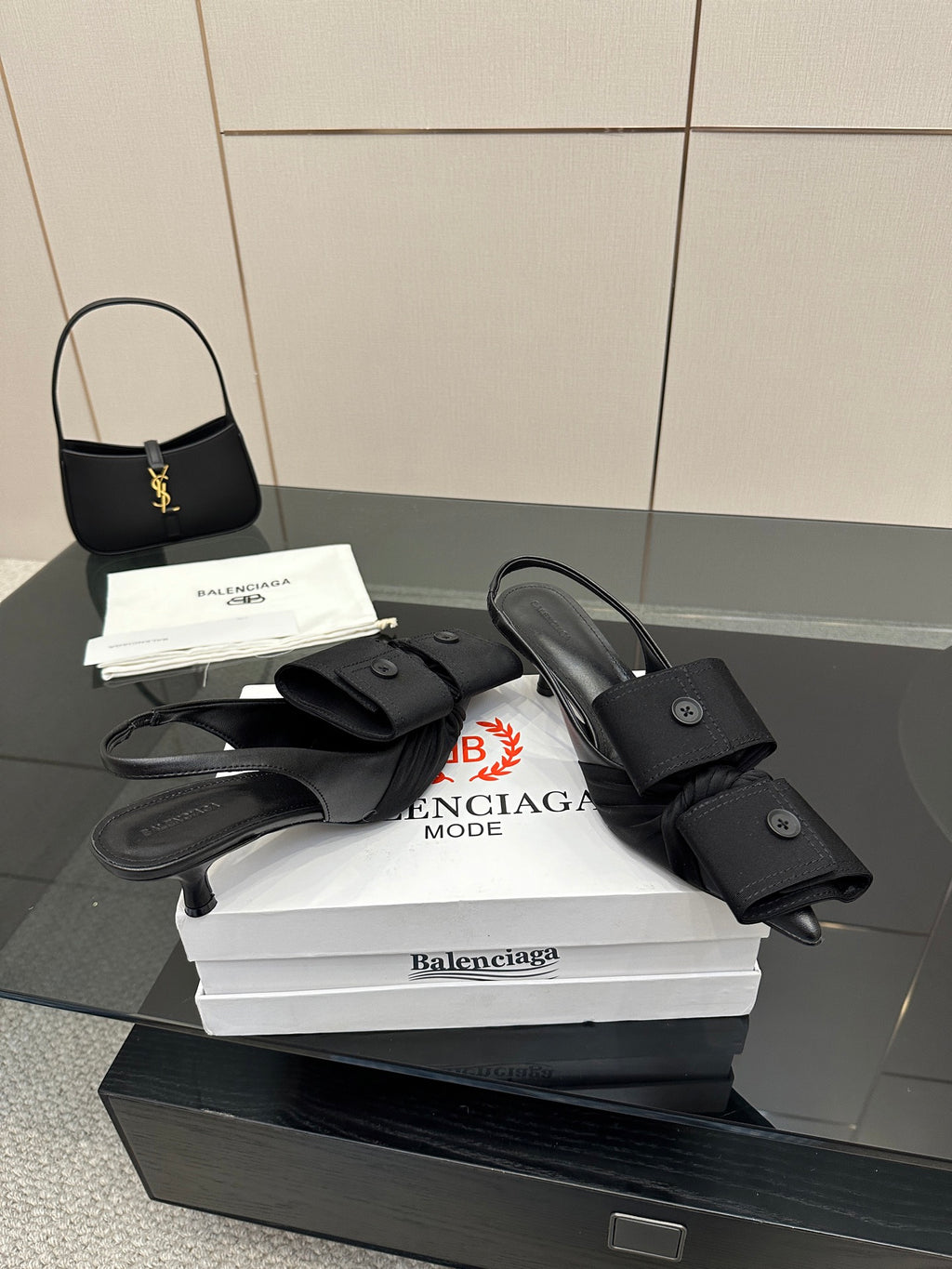 Black mules with buckled straps and low block heel, on white Balenciaga box