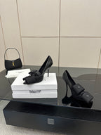 Black pointed-toe high heel slingback shoes with ankle wrap straps and button closures