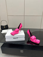 Pink pointed-toe stiletto heels with front bow-tie strap and button accents