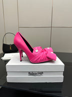 Pink pointed-toe high-heel pump with knotted bow strap at the toe