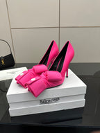 Pink pointed-toe pumps with gathered bow strap and round button accents