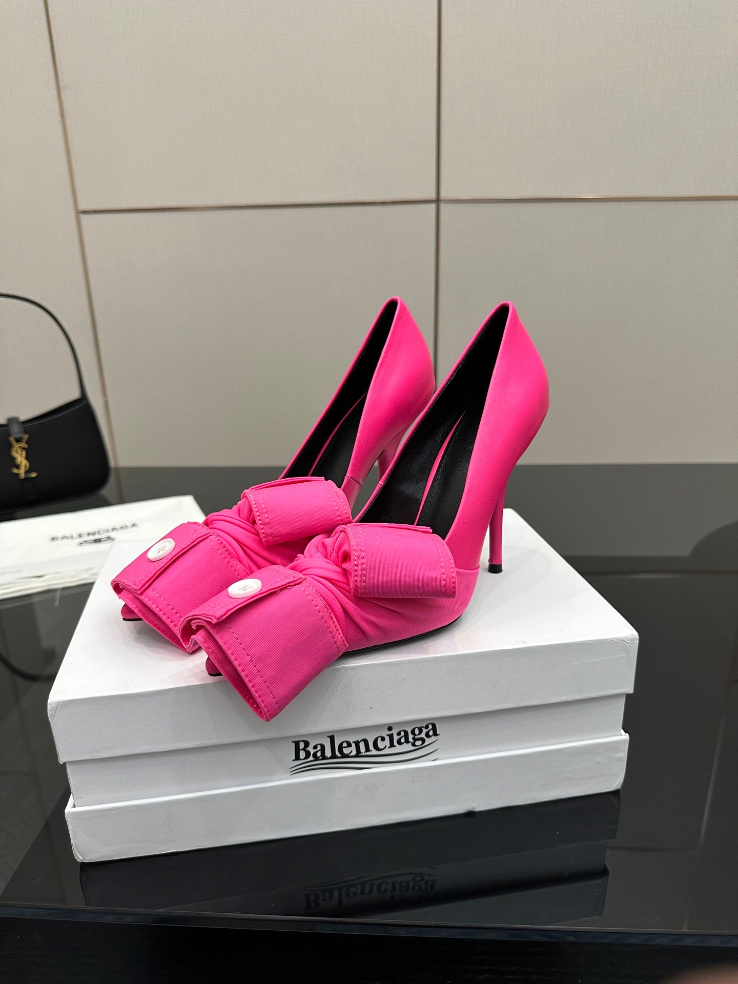 Pink pointed-toe pumps with gathered bow strap and round button accents