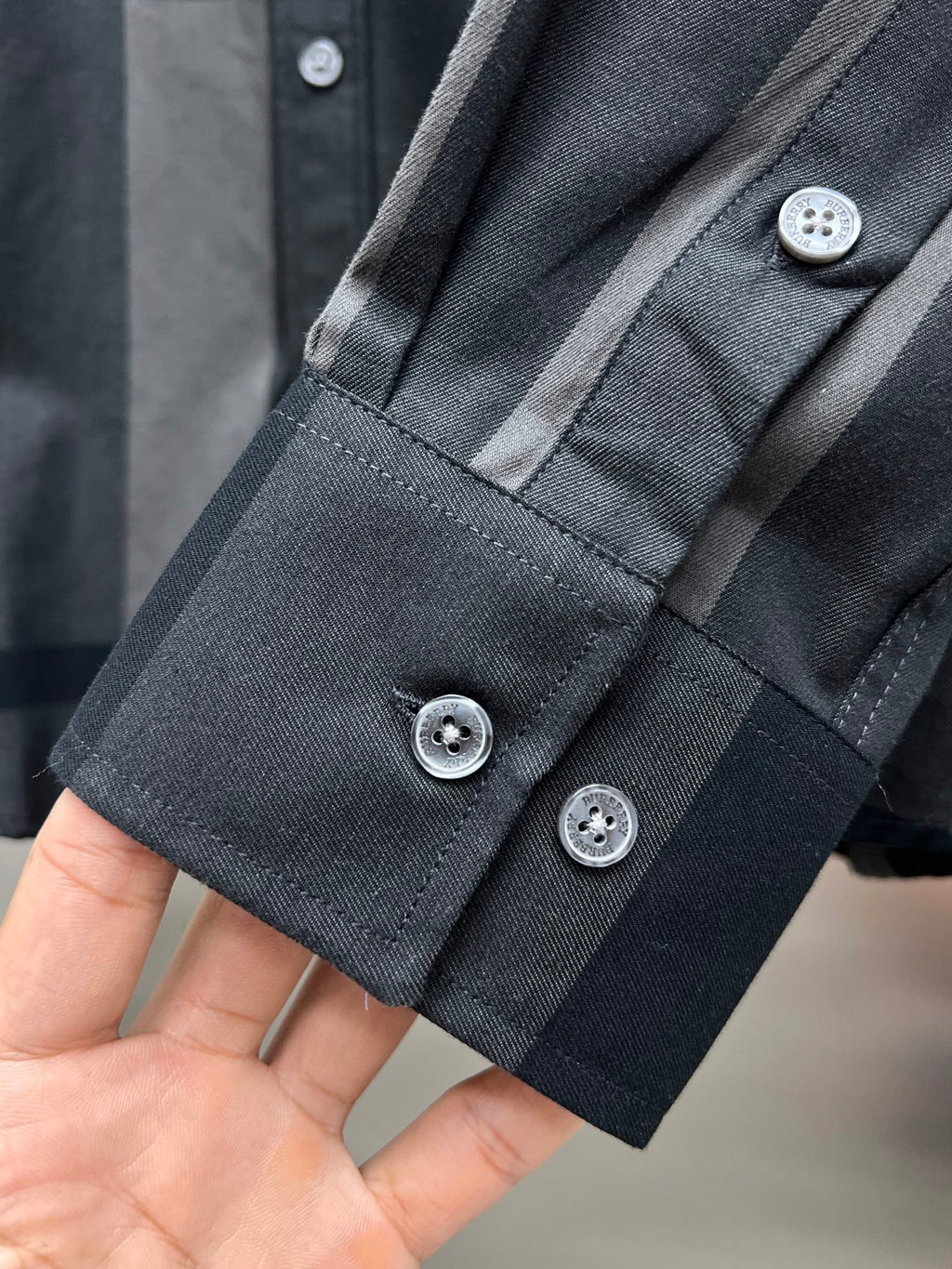 Long-sleeve button-up shirt cuff with three button closures and stitched placket