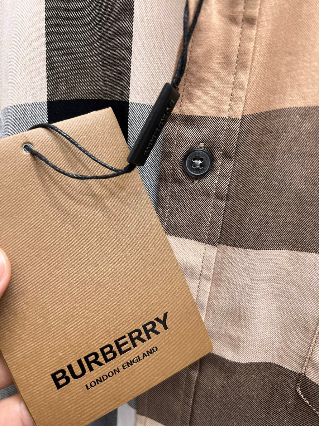Burberry woven neck label on beige plaid button-up shirt fabric close-up