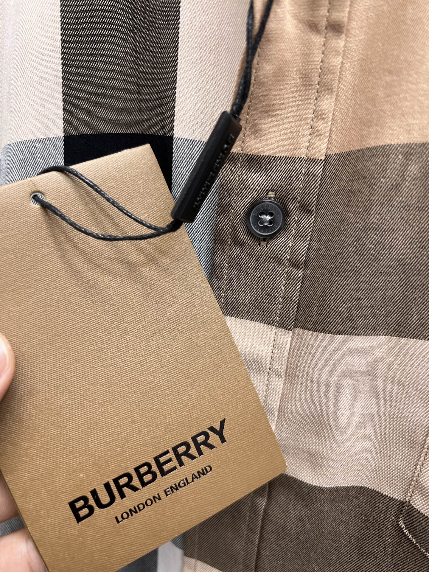 Burberry woven neck label on beige plaid button-up shirt fabric close-up