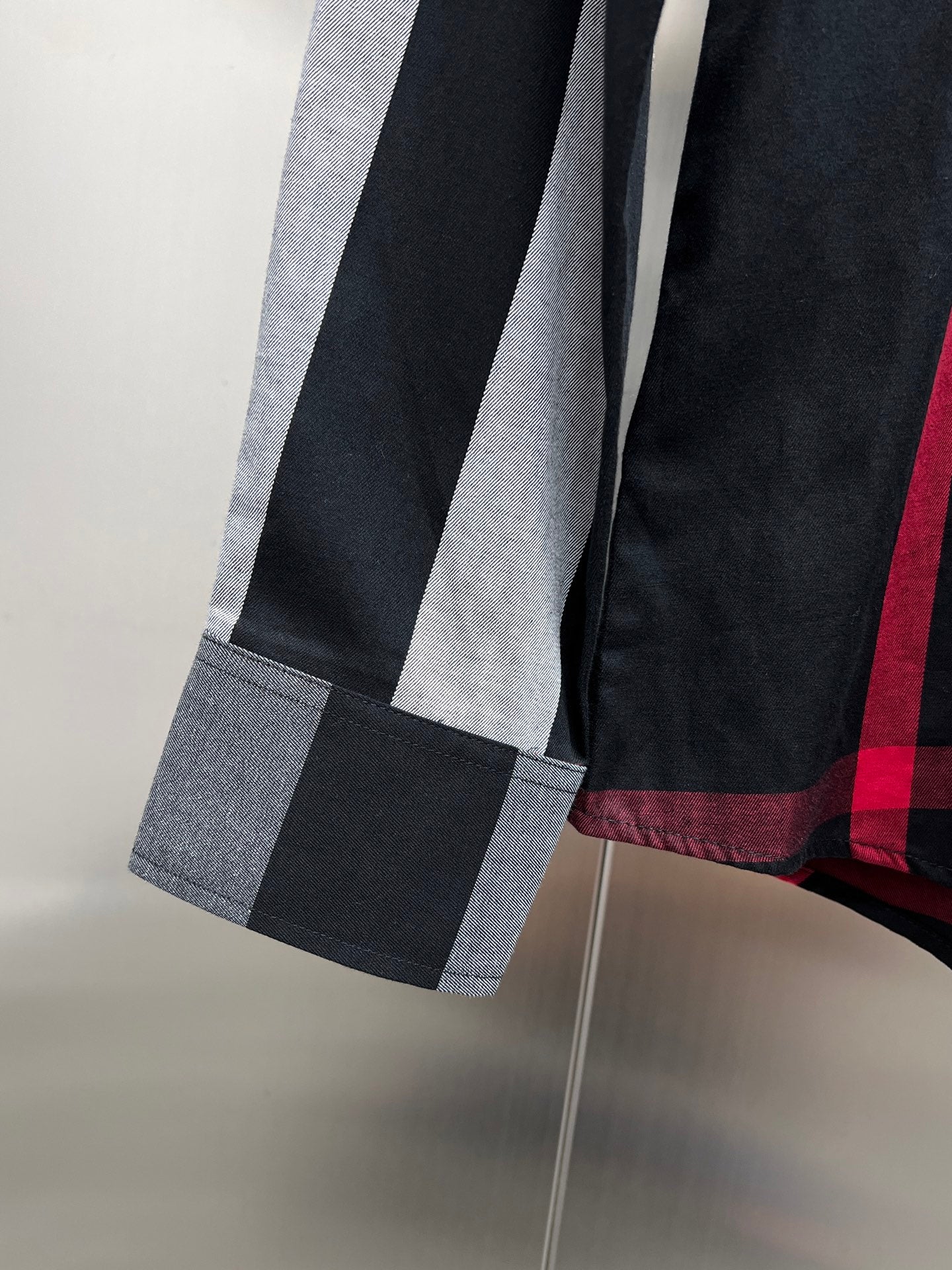 Burberry long-sleeve check shirt cuff with dark/gray stripes and red plaid hem