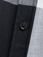 Round black button on front placket of a black-and-white plaid button-up shirt