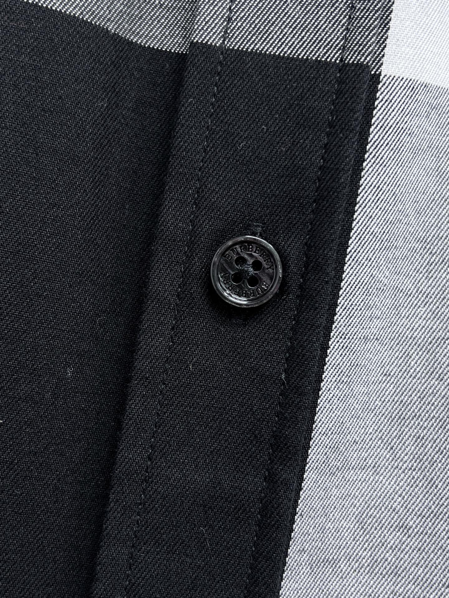 Round black button on front placket of a black-and-white plaid button-up shirt