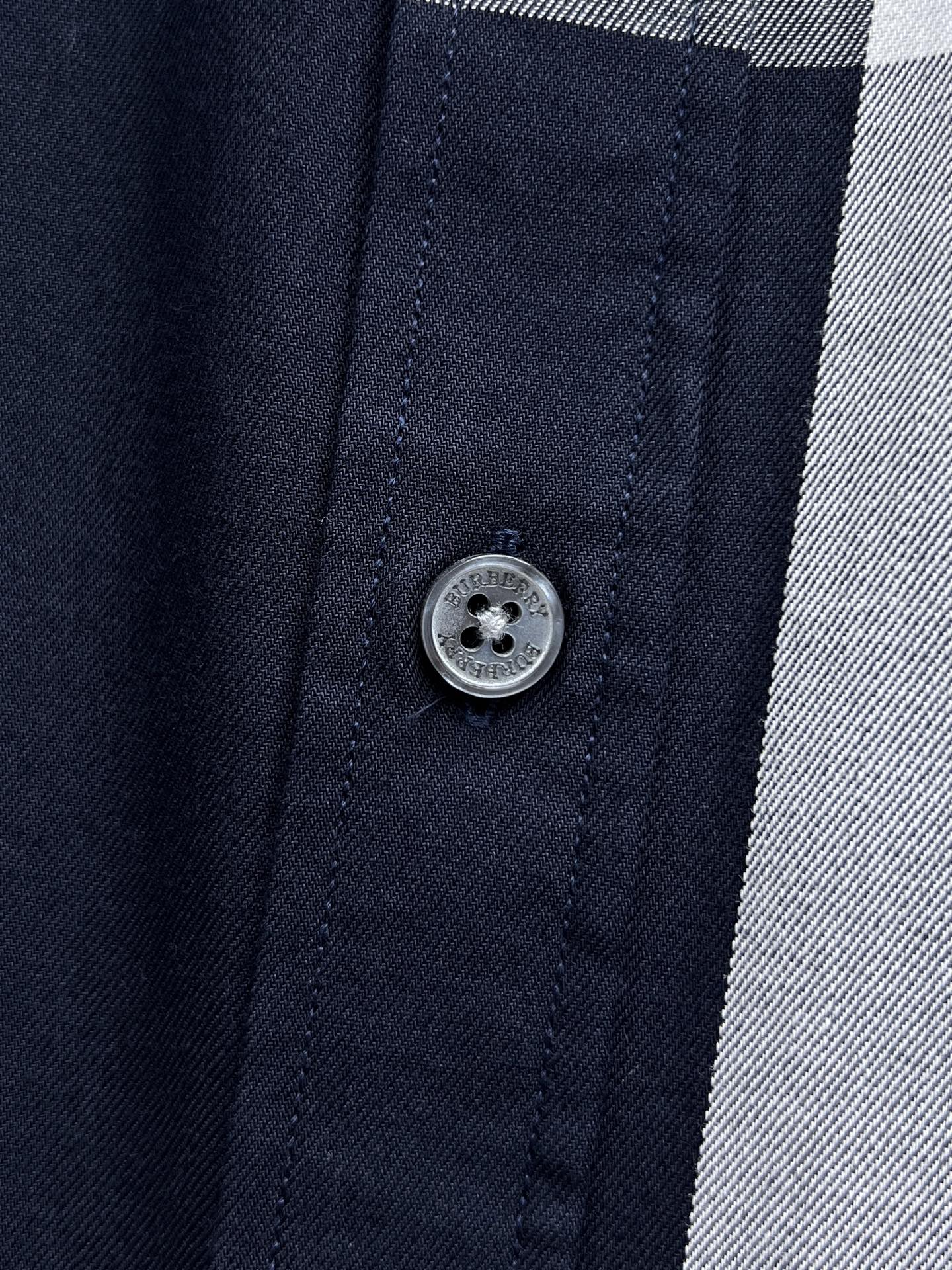 Burberry shirt button close-up on navy fabric with stitched placket