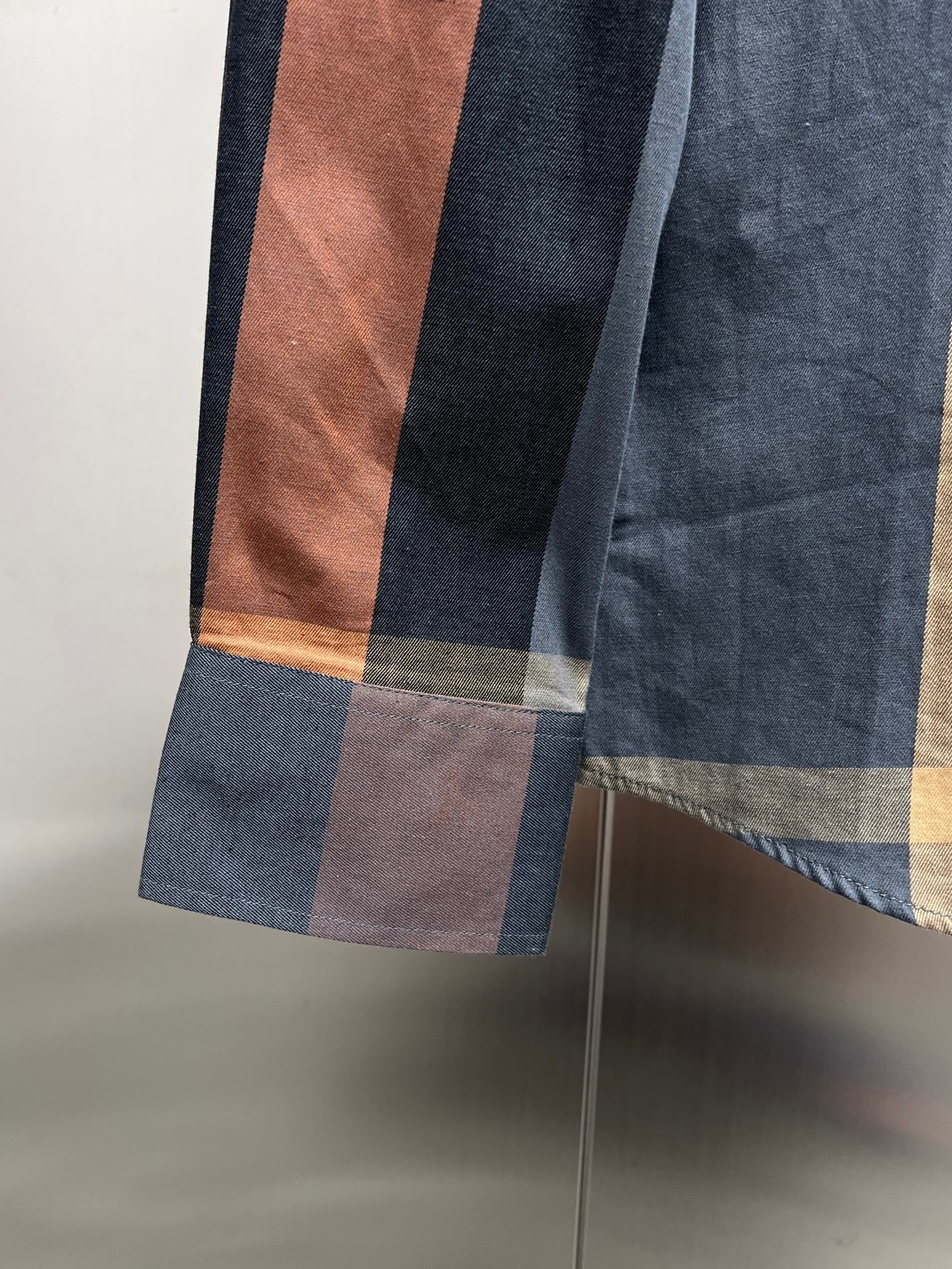 Plaid long-sleeve shirt hem detail with stepped pattern and cuff panel