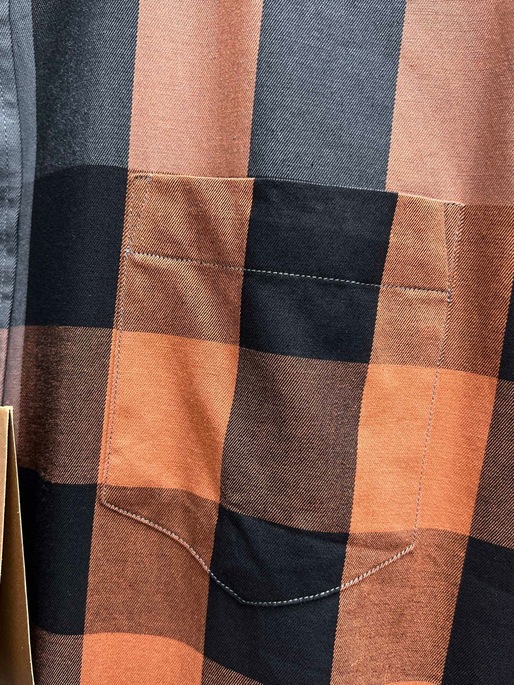 Plaid long-sleeve shirt pocket detail with tan-brown check and contrast stitching