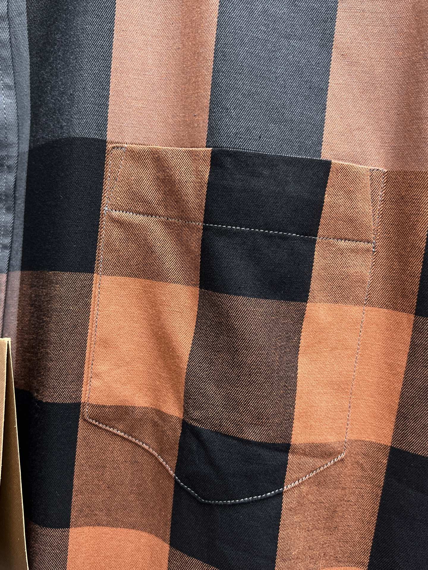 Plaid long-sleeve shirt pocket detail with tan-brown check and contrast stitching