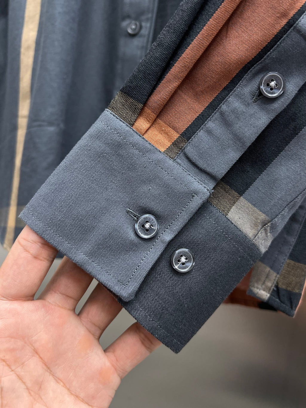 Long-sleeve shirt cuff detail with blue and brown plaid and two button closures