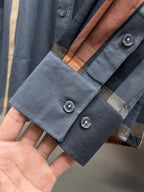 Long-sleeve shirt cuff detail with blue and brown plaid and two button closures