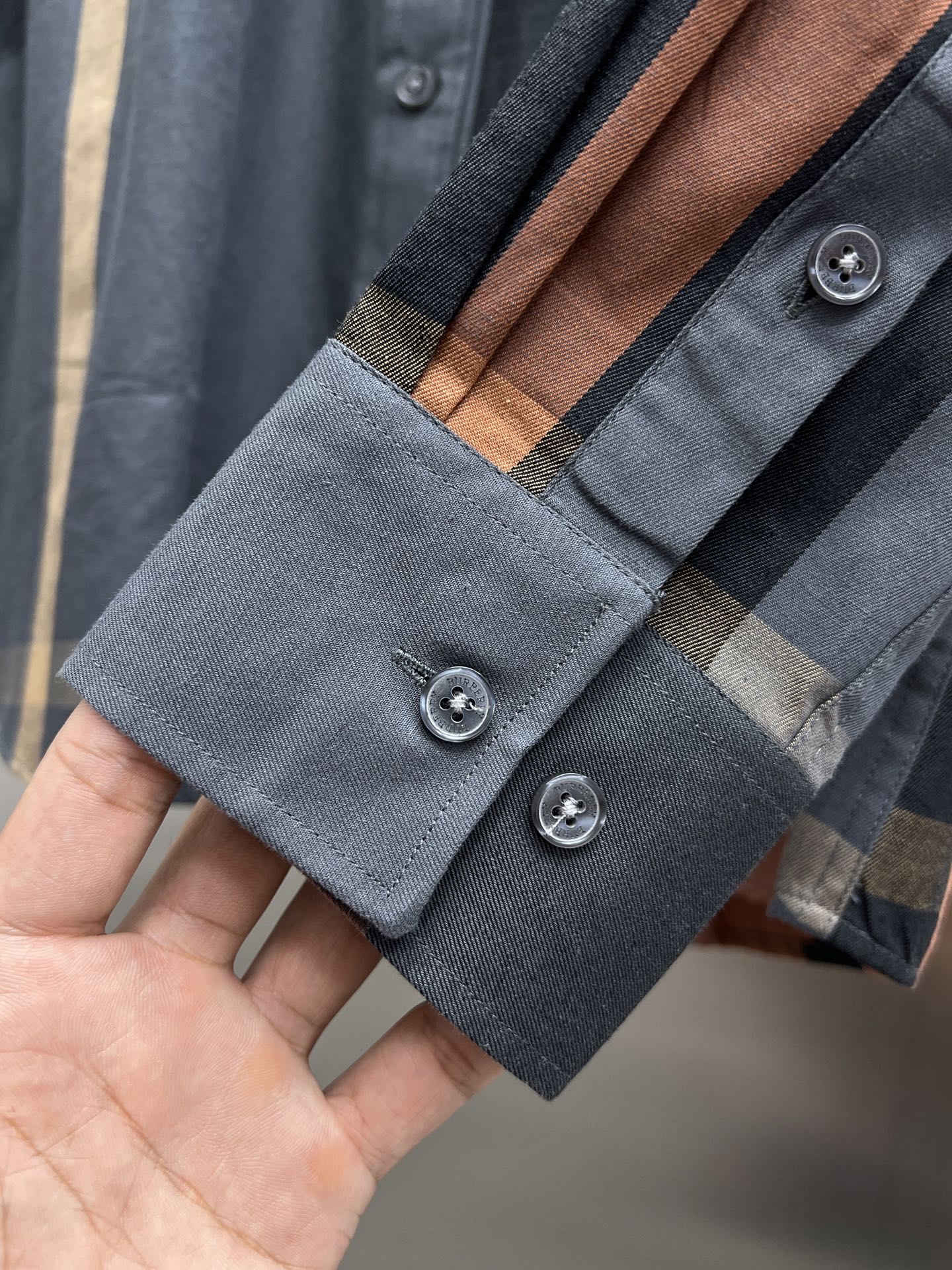 Long-sleeve shirt cuff detail with blue and brown plaid and two button closures