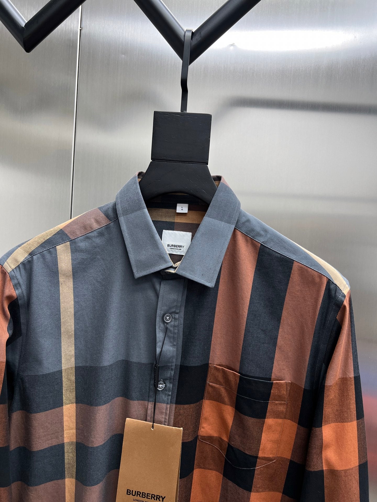Plaid long-sleeve button-up shirt close-up at collar and front with brand tag