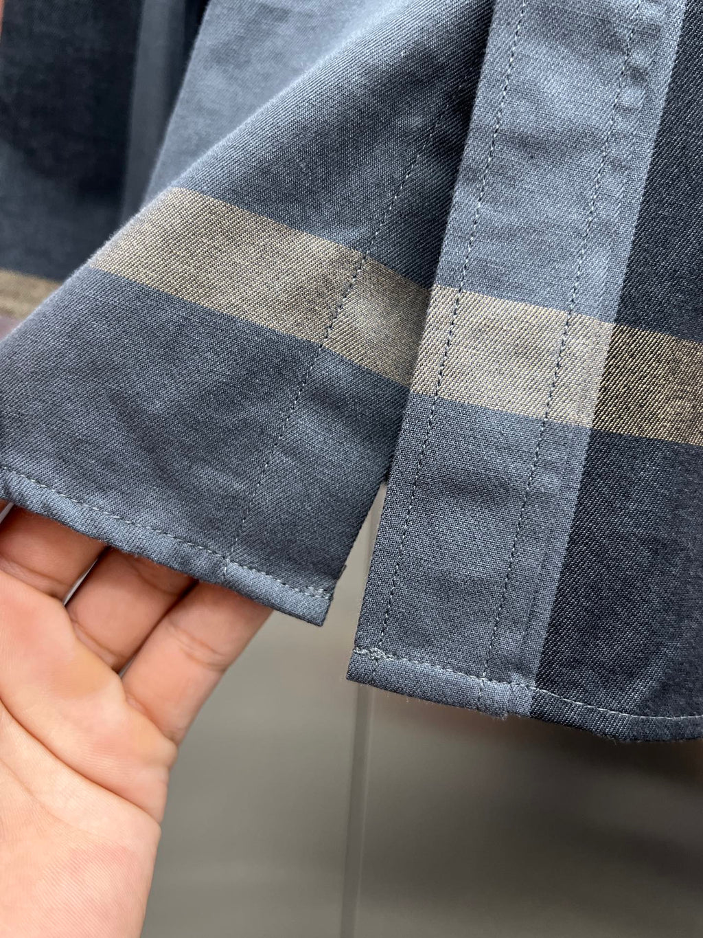 Long-sleeve shirt cuff with blue, beige plaid trim and buttoned sleeve end