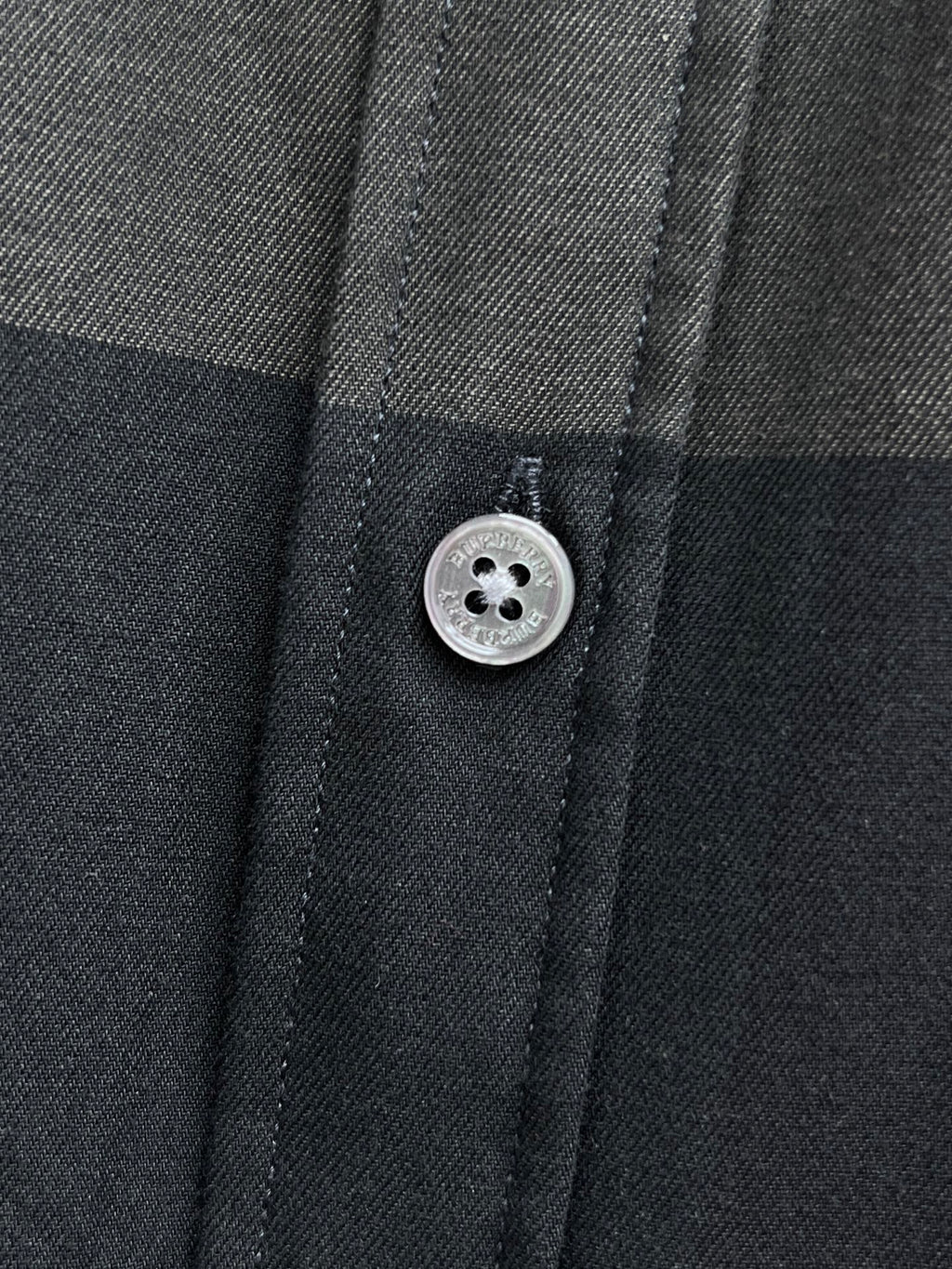 Burberry plaid button-up shirt button close-up, dark gray fabric