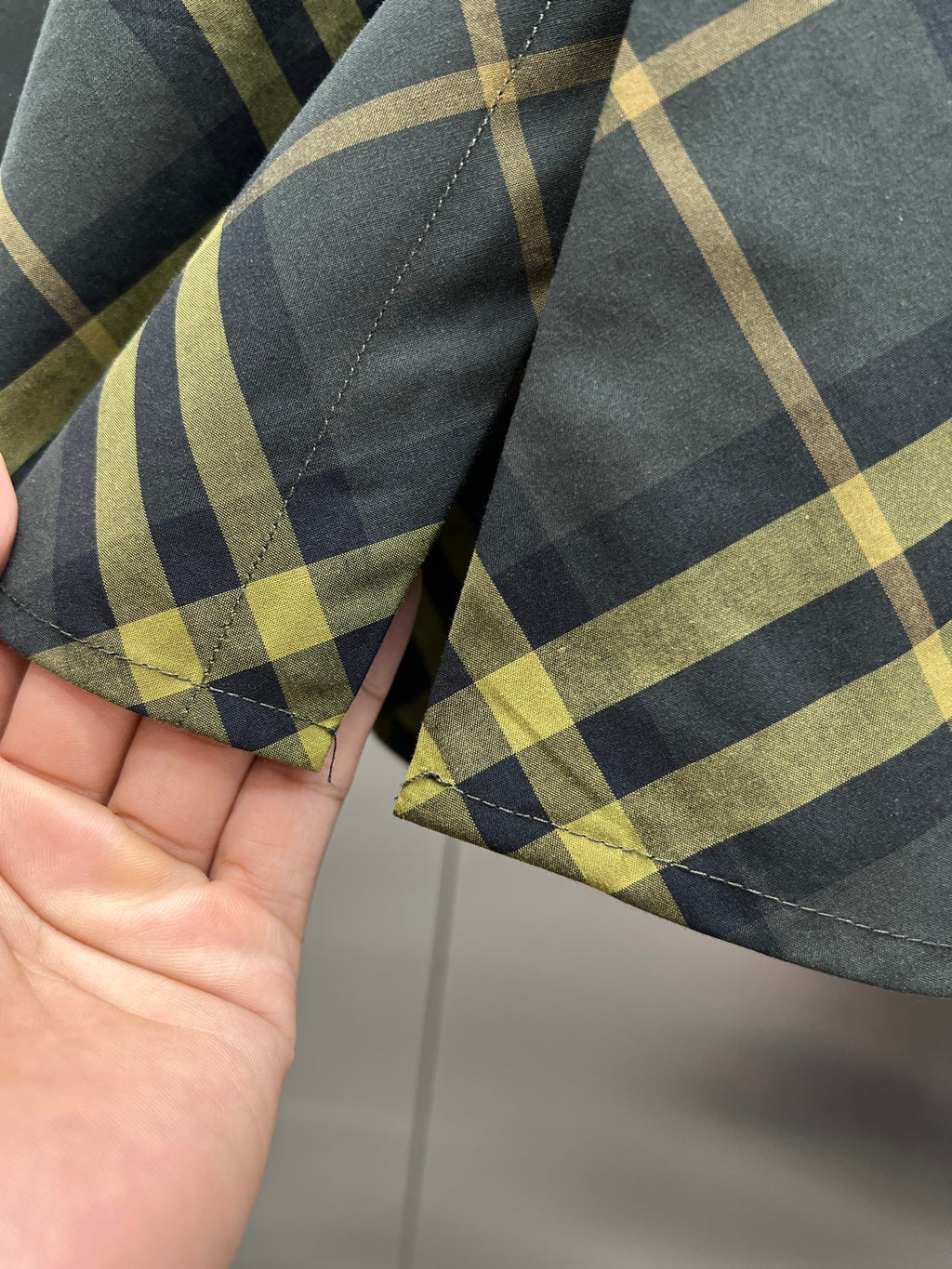 Plaid shirt sleeve cuff close-up with stitched seam and button area