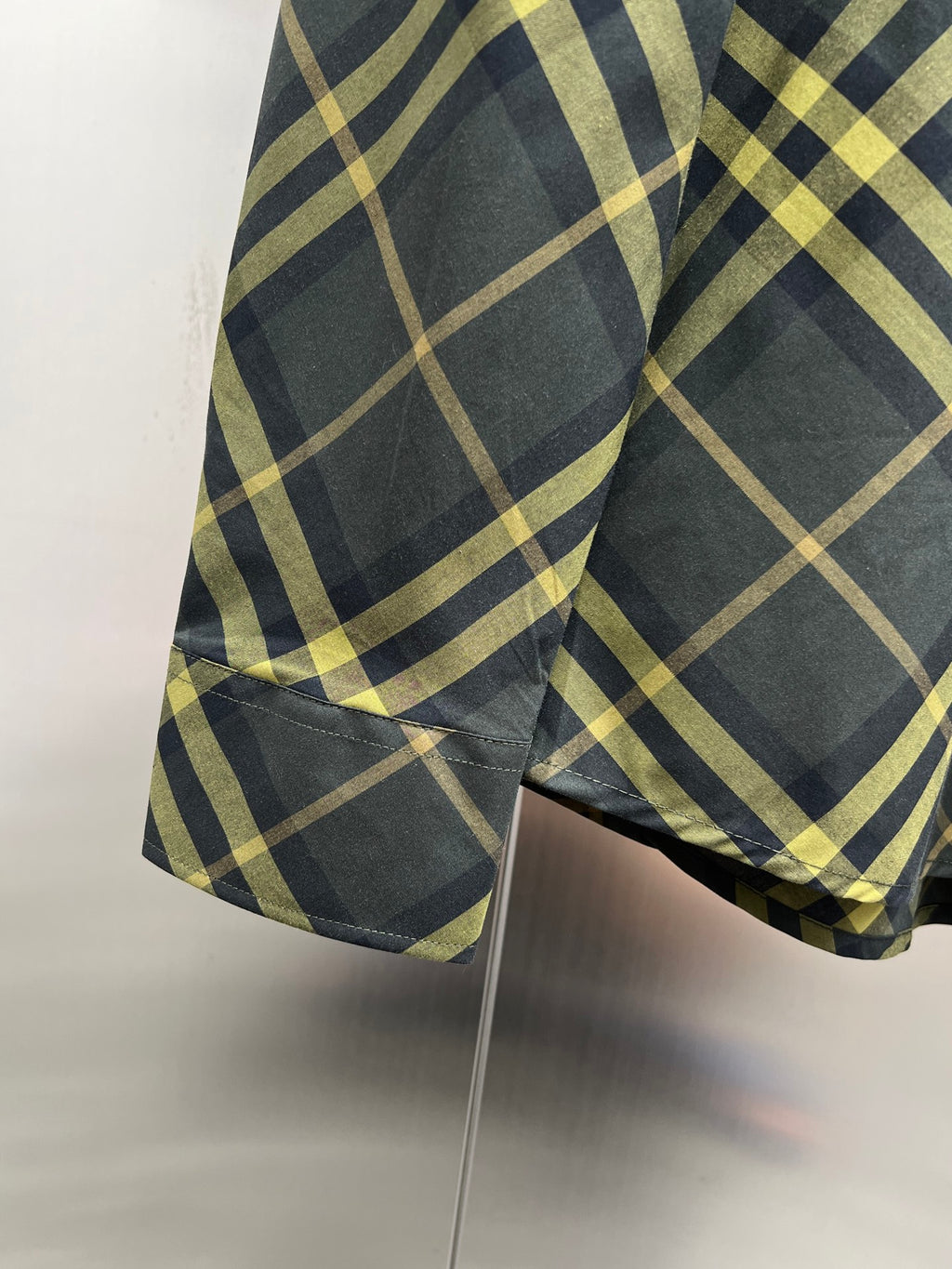Plaid long-sleeve button-up shirt side view with curved hem and sleeve cuff