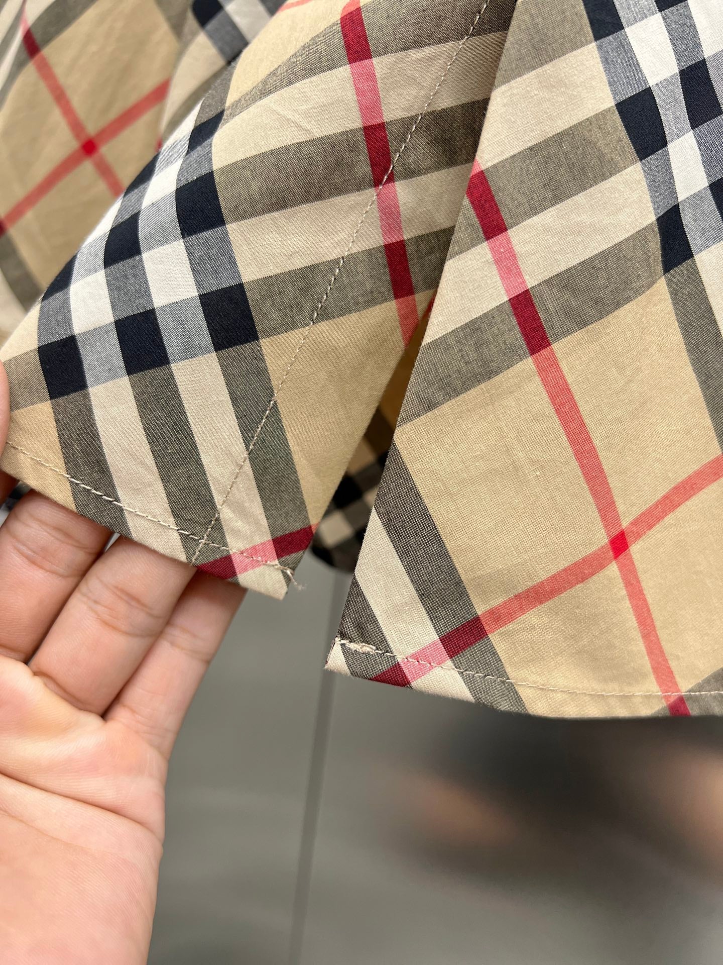 Burberry plaid shirt fabric close-up with beige, black, white, and red lines