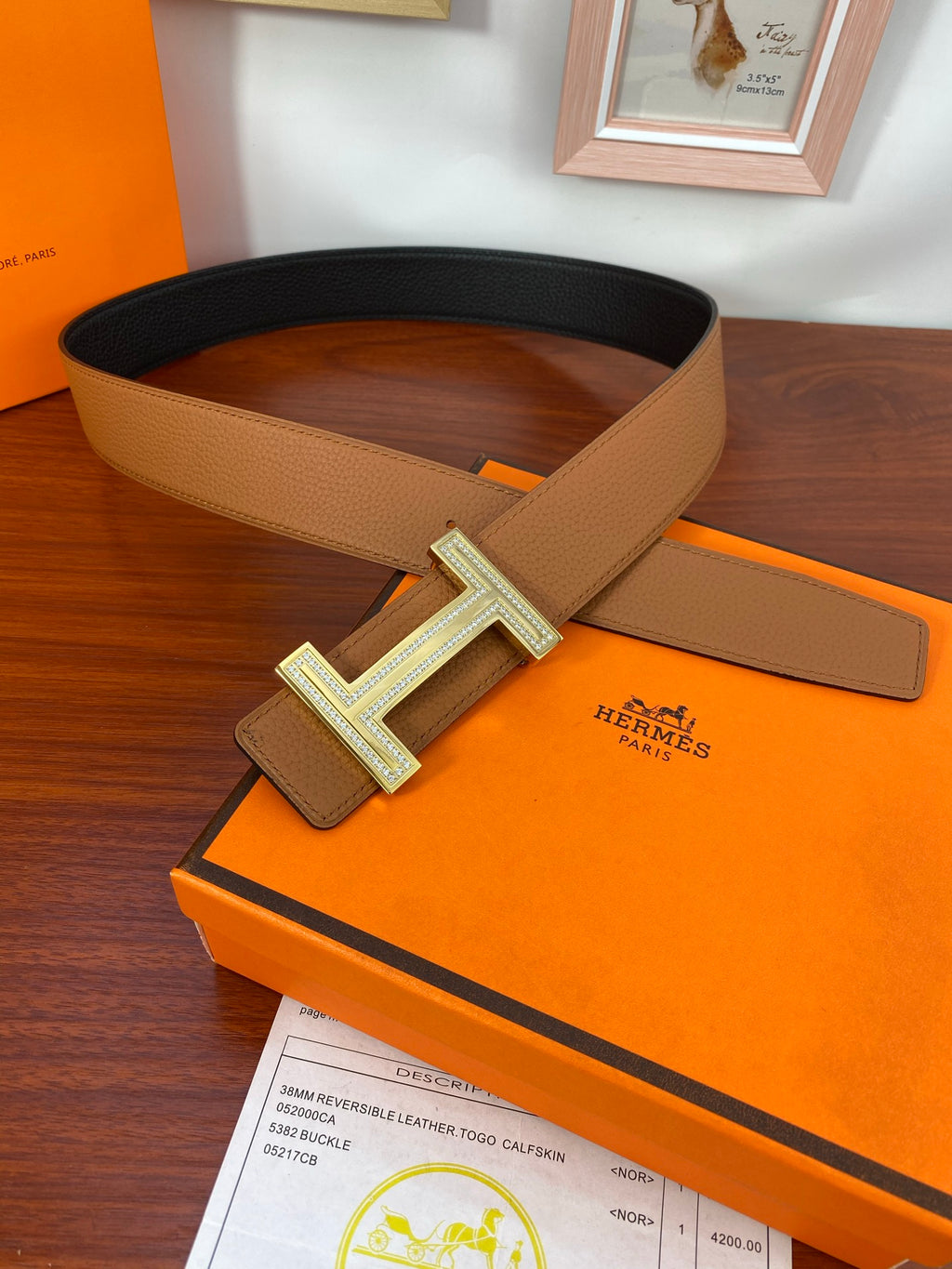 Reversible leather belt on box, tan and black straps with gold-tone H buckle