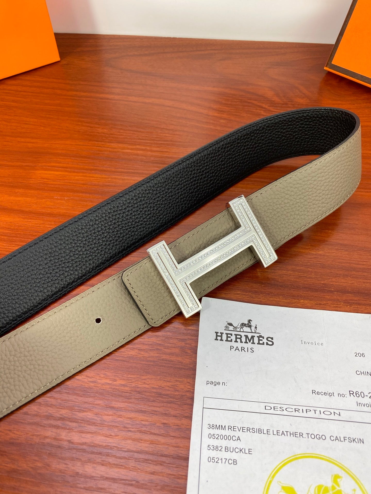 Leather belt with light gray strap and dark back, silver H buckle in front