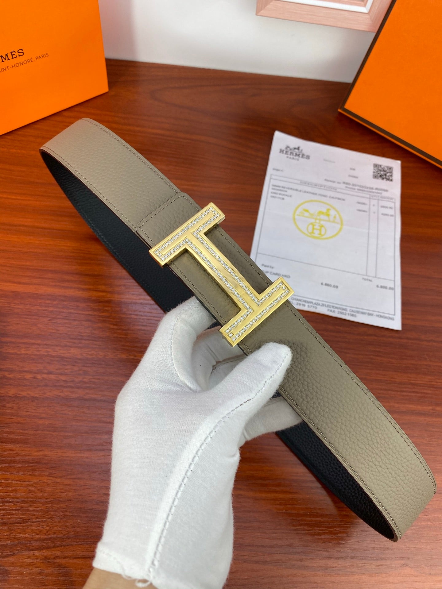 Leather belt with light gray strap, dark underside, and silver H buckle detail