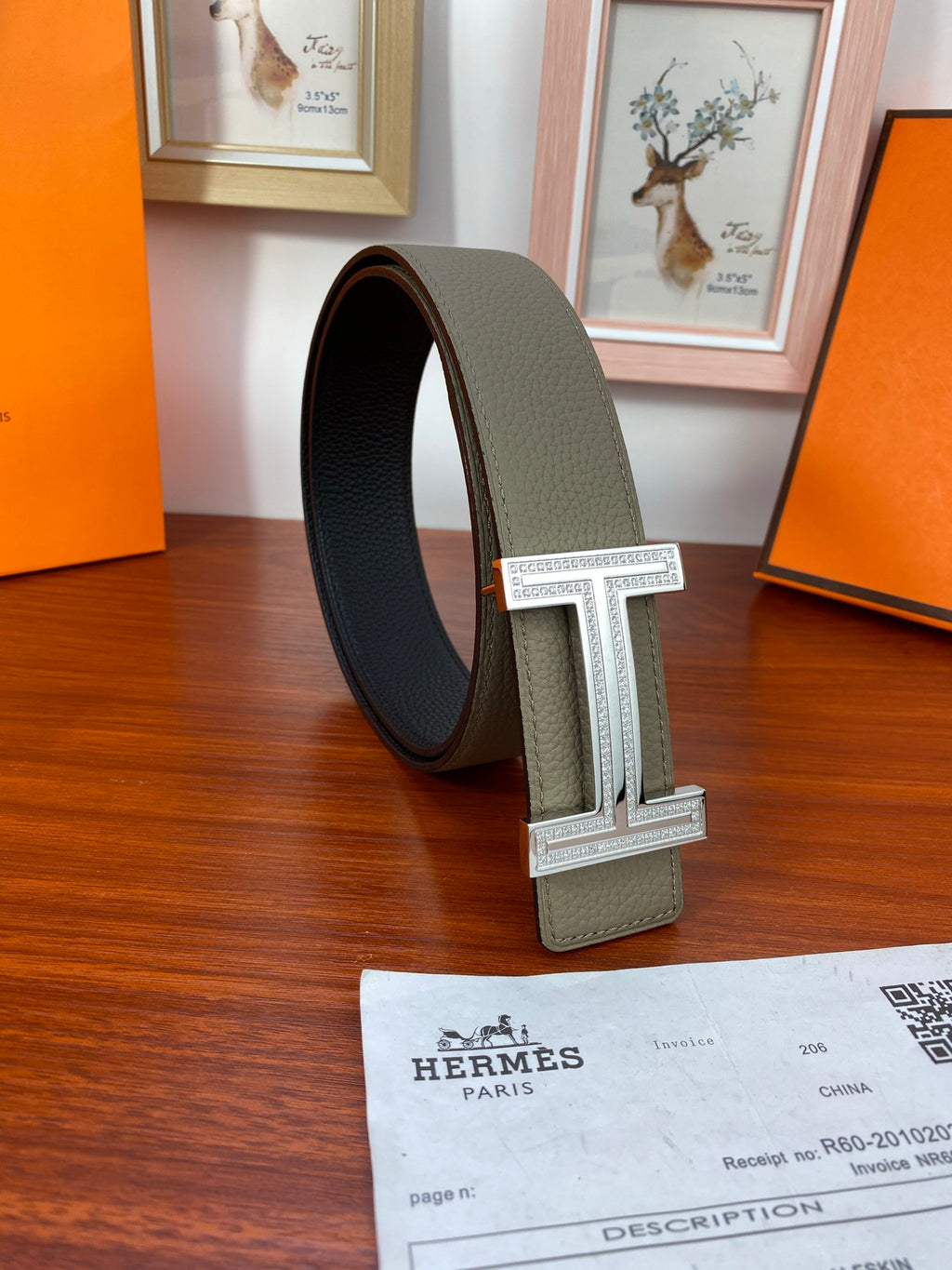 Leather belt looped around, light gray strap with dark reverse and silver H buckle